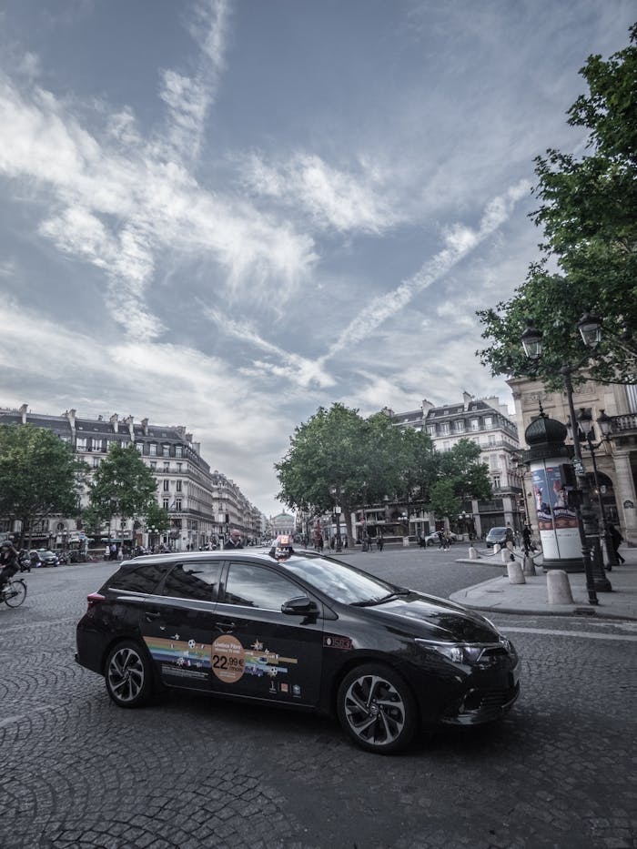 heros-img A sleek black car parked on a cobblestone street in Paris, capturing urban life and classic architecture.